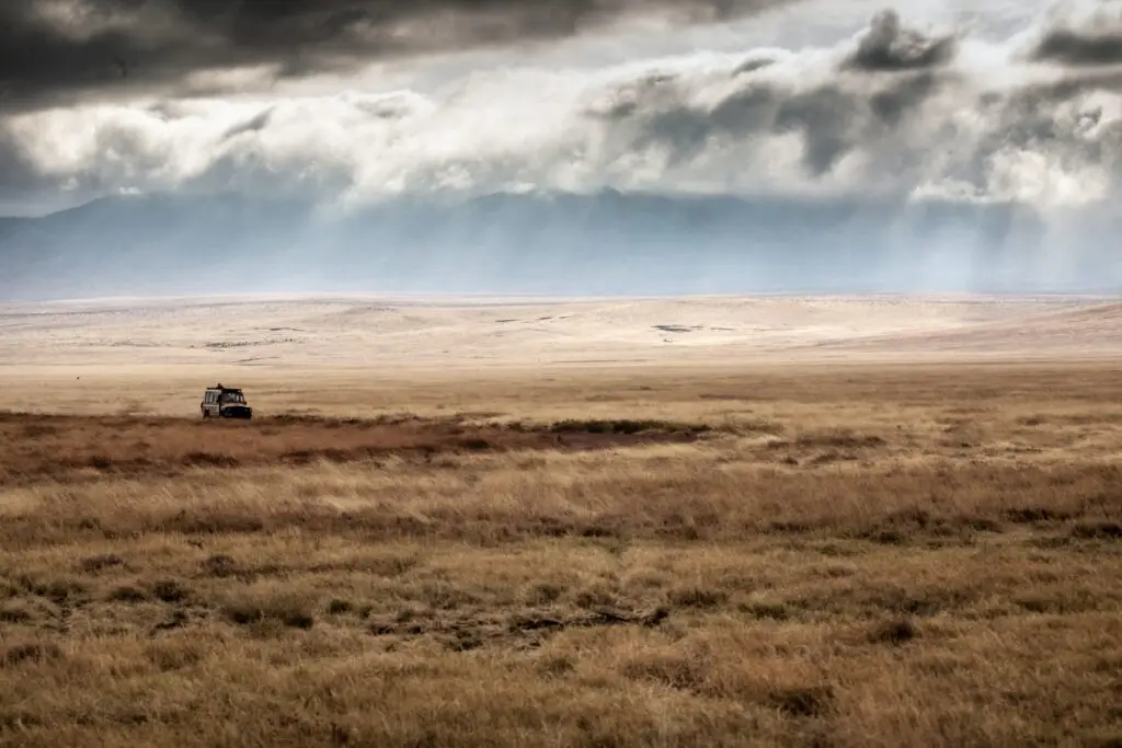 4x4 de safari dans les plaines du Ngorongoro en Tanzanie, avec des rayons de soleil perçant les nuages.