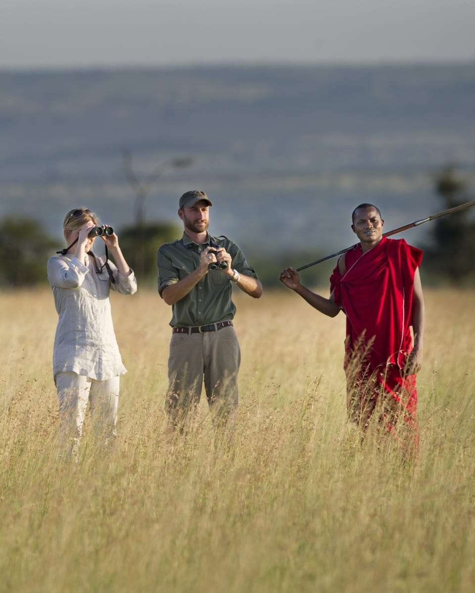 Honeymoon couple on safari in Tanzania with a local guide in the savannah