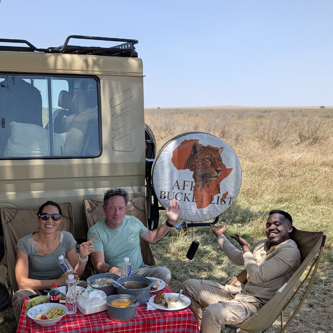 Voyageurs déjeunant en pique-nique à côté de leur 4x4 de safari privé